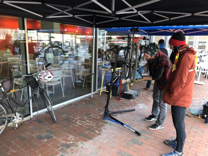 Photo of mechanic fixing a bicycle on the Safra Plaza, outside of the Smith Campus Center