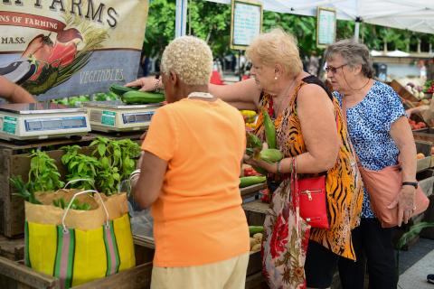 Women shopping at a vegetable stand at the Farmers' Market at Harvard